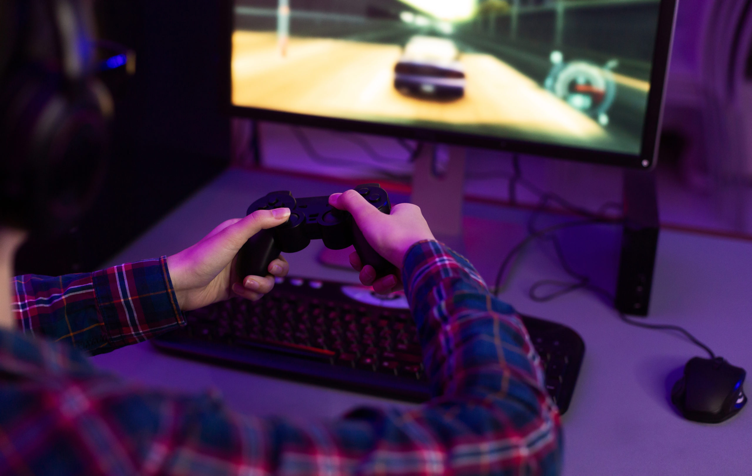 Gamer playing a game with controller in front of screen.