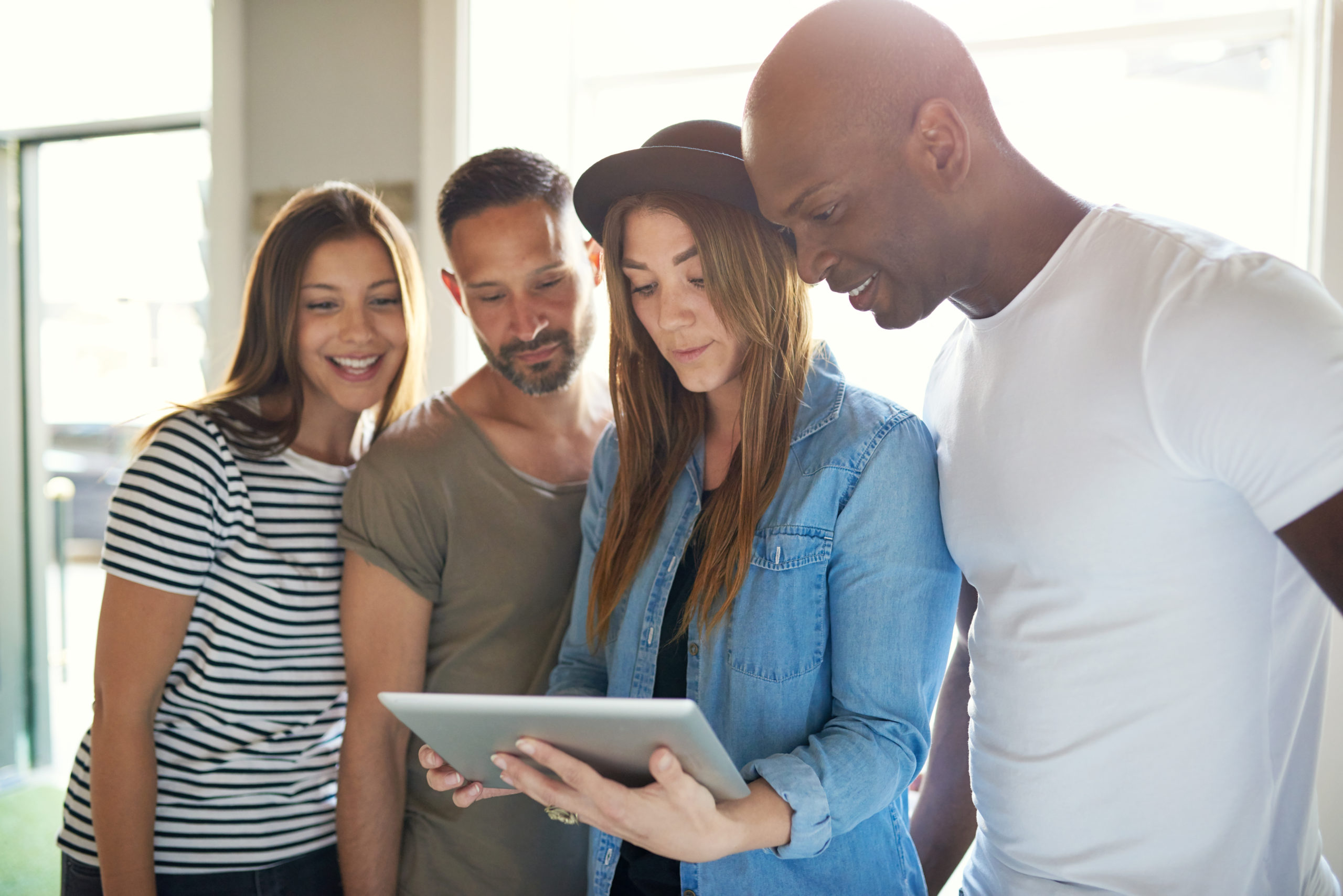 Four adults looking at something on a tablet.