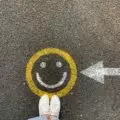 pavement with happy face and woman standing just above it